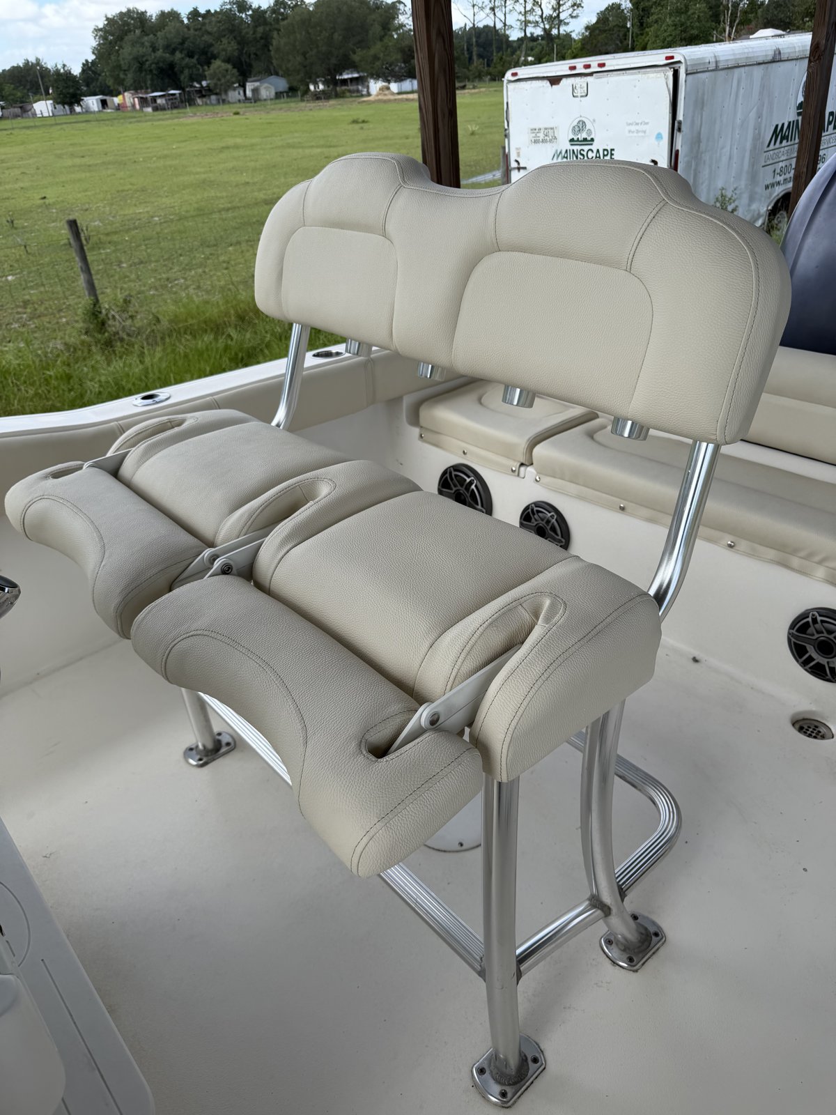 Helm seat with flip-up bolsters reupholstered in cream vinyl on a center console boat